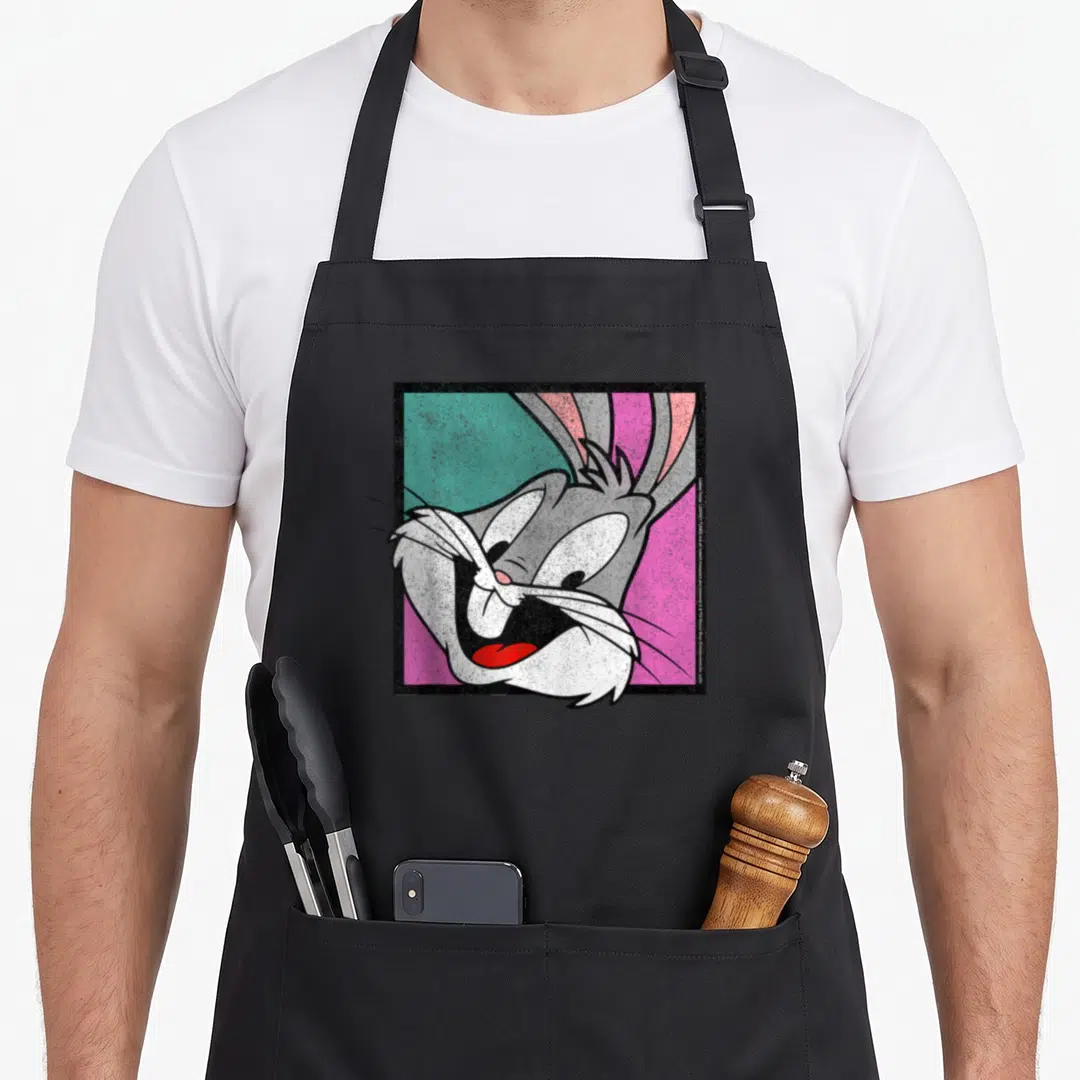 Box bunny apron - Bugs Bunny head over teal pink diagonal square, grey white fur, black border — shown on a black cotton canvas apron against a white background