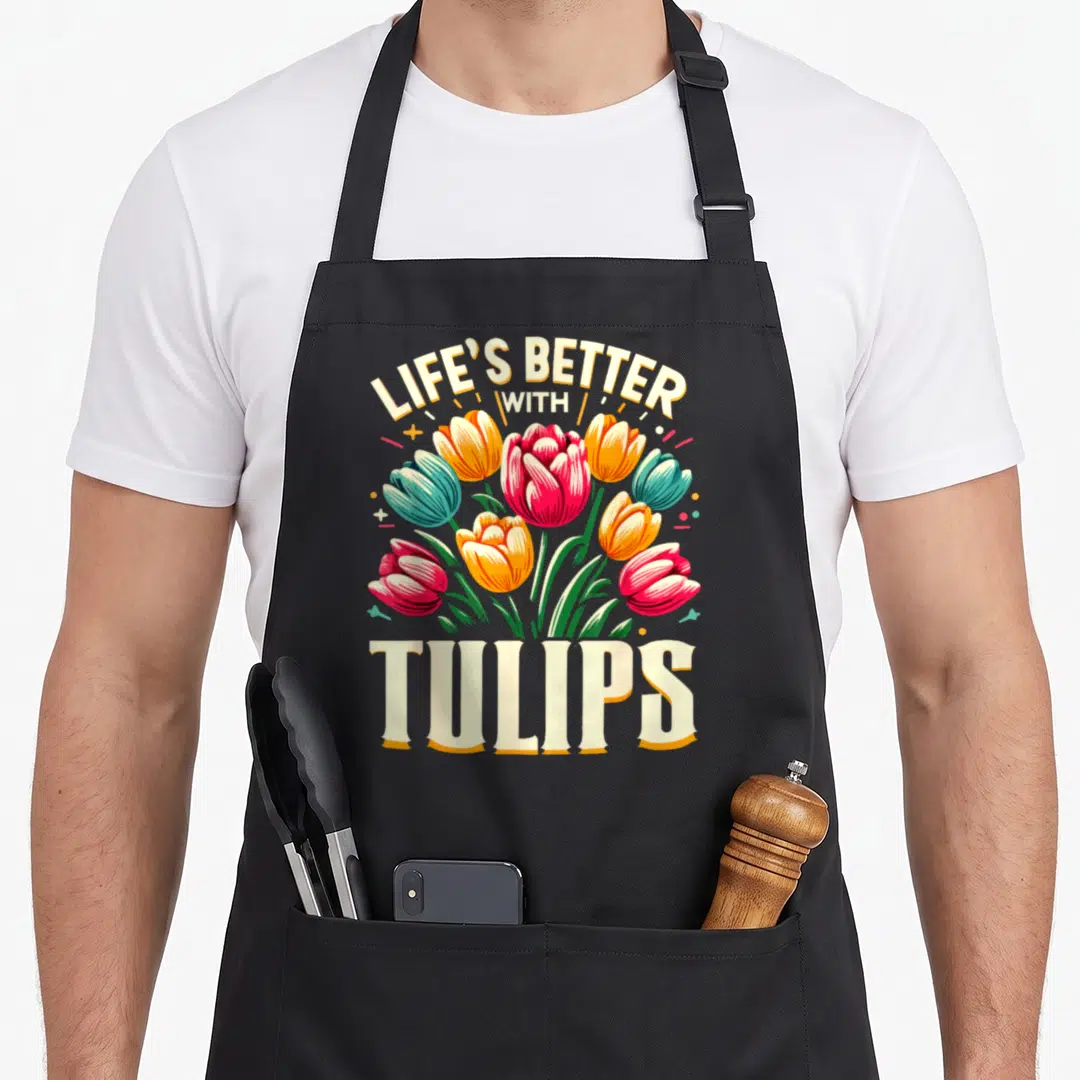 Floral tulip apron - Arched LIFE'S BETTER WITH TULIPS text above red orange teal and cream tulip bouquet — shown on a black cotton canvas apron against a white background