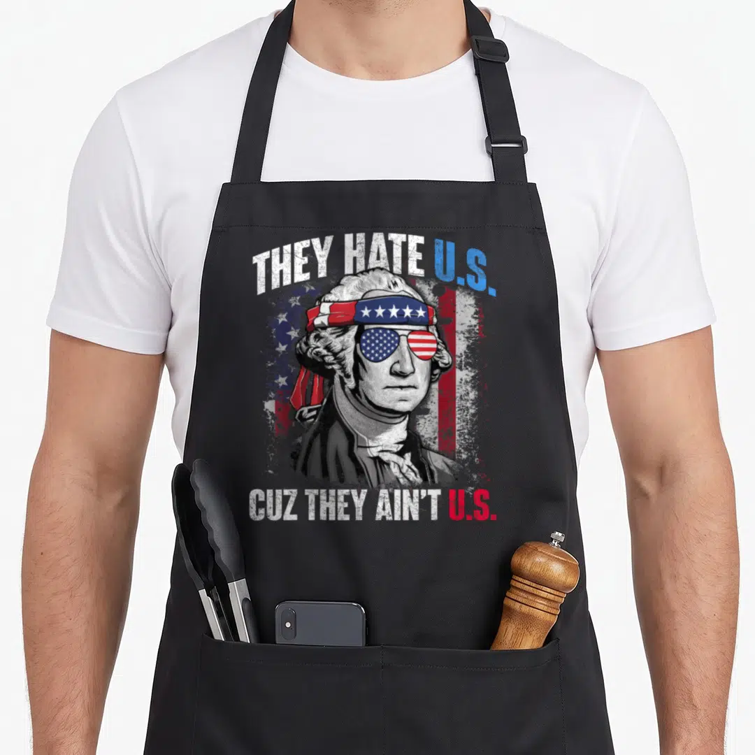 They 4th of july apron - George Washington in flag sunglasses with They Hate Us Cuz They Ain't Us text — shown on a black cotton canvas apron against a white background
