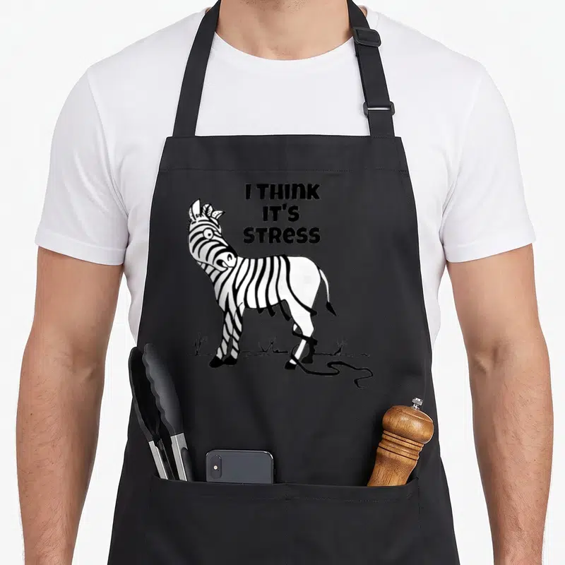 Stripe zebra apron - I THINK IT'S STRESS text beside a black and white cartoon zebra — shown on a black cotton canvas apron against a white background