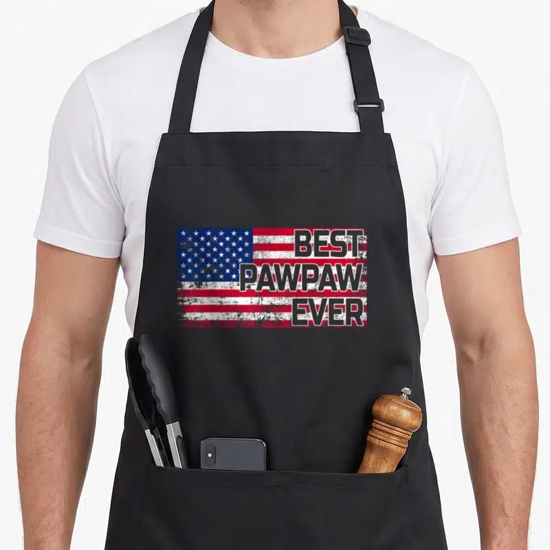 Pawpaw american flag apron - Distressed USA flag with stacked BEST PAWPAW EVER text in gray — shown on a black cotton canvas apron against a white background