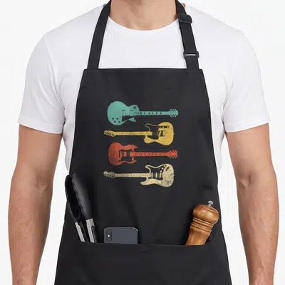 Music guitarist apron - Four distressed electric guitars in teal, yellow, red, and cream stacked vertically — shown on a black cotton canvas apron against a white background