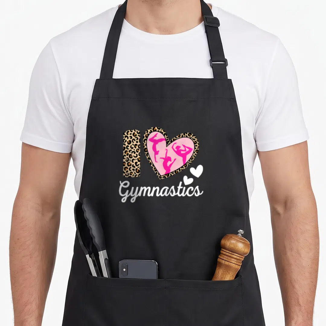 Tumbling gymnastics apron - Leopard I and heart with three pink gymnasts above white Gymnastics script and two small — shown on a black cotton canvas apron against a white background