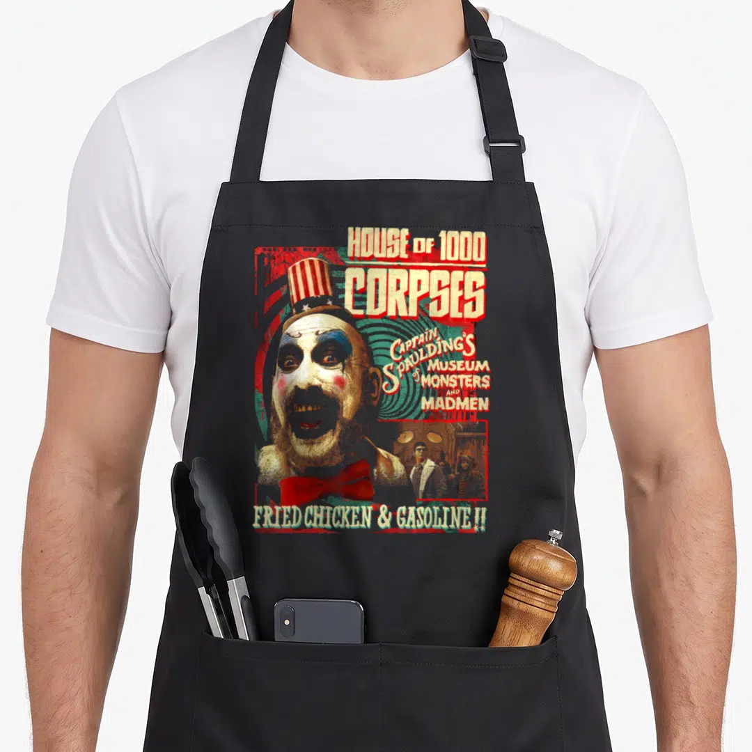 Captain zombie apron - Distressed clown head with House of 1000 Corpses text and Fried Chicken Gasoline slogan — shown on a black cotton canvas apron against a white background