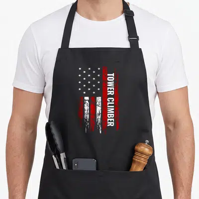 Tower american flag apron - Vertical Tower Climber text on a distressed red and white USA flag graphic — shown on a black cotton canvas apron against a white background