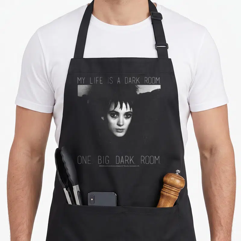 Lydia beetle apron - Woman's face with text My Life Is A Dark Room in grey and white on black background — shown on a black cotton canvas apron against a white background