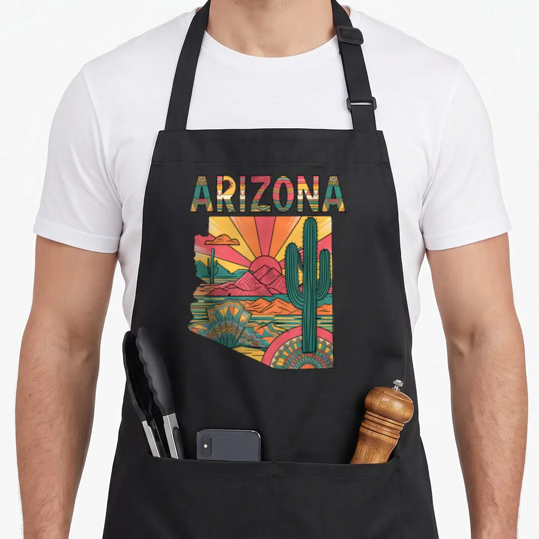 Arizona flag cactus apron - Retro Arizona state map print with cacti, mountains, and sun in orange, green, pink — shown on a black cotton canvas apron against a white background