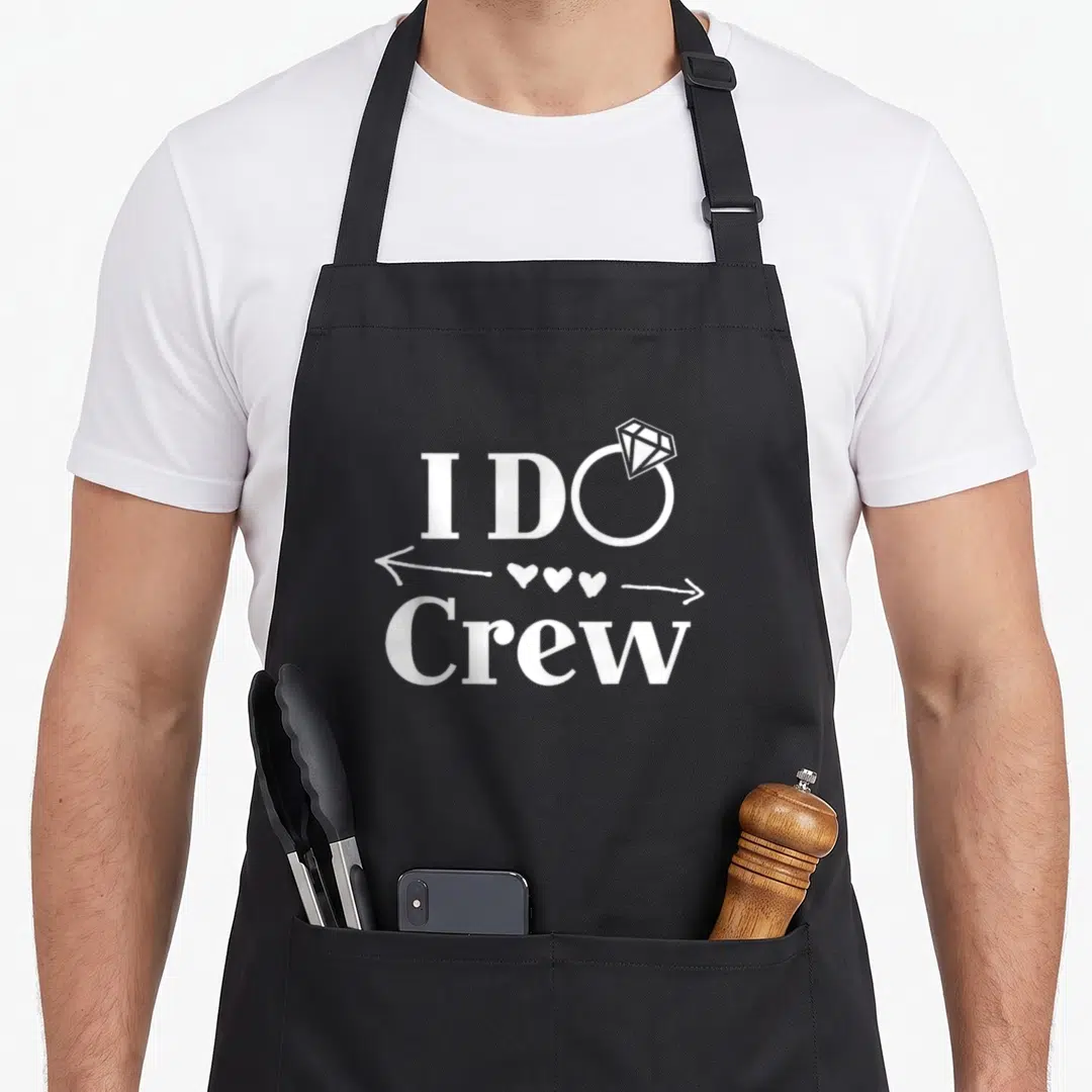 Crew wedding apron - White I DO Crew text with diamond ring and three hearts on black bib — shown on a black cotton canvas apron against a white background