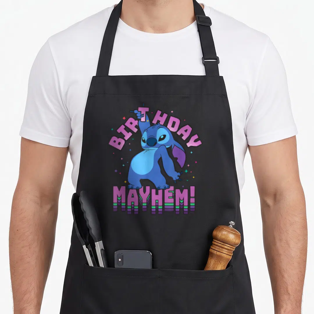 Disco birthday apron - Stitch character with BIRTHDAY MAYHEM text in pink and purple surrounded by stars — shown on a black cotton canvas apron against a white background