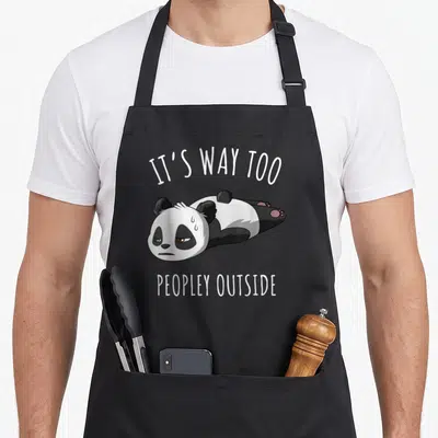Way kawaii apron - Lying cartoon panda with IT'S WAY TOO PEOPLEY OUTSIDE text in white and grey — shown on a black cotton canvas apron against a white background