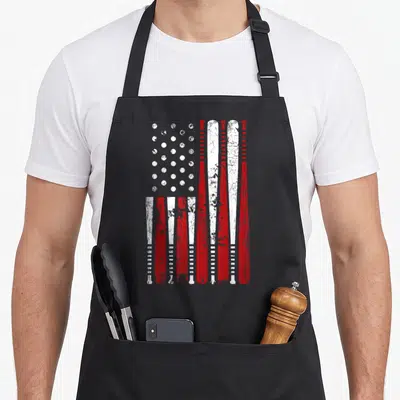 Baseball bat american flag apron - Red and white flag design made of vertical bats and a grid of baseballs — shown on a black cotton canvas apron against a white background