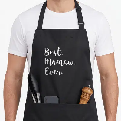 Mamaw grandma apron - White cursive text reading Best Mamaw Ever stacked in three lines — shown on a black cotton canvas apron against a white background
