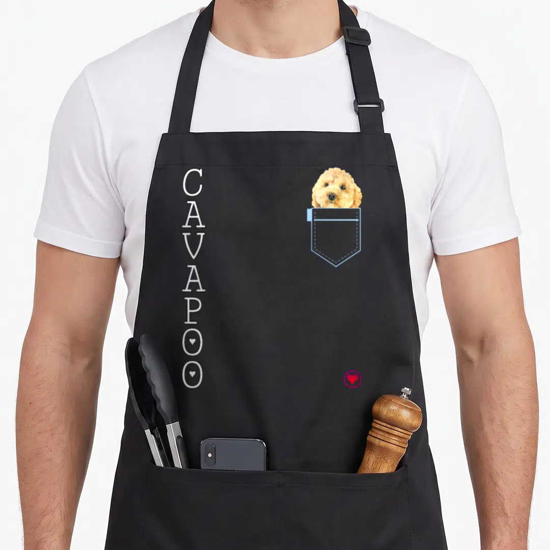Cross dog apron - Vertical CAVAPOO text next to tan dog head in light blue pocket on grey background — shown on a black cotton canvas apron against a white background