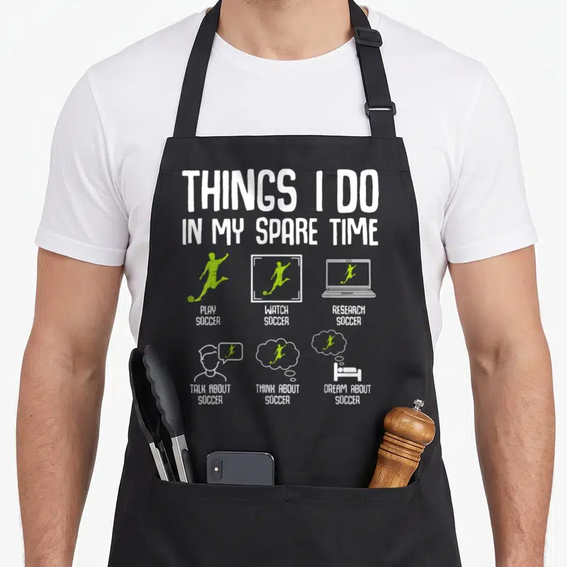 Spare soccer player accessories apron - Text listing playing watching researching talking thinking and dreaming about — shown on a black cotton canvas apron against a white background