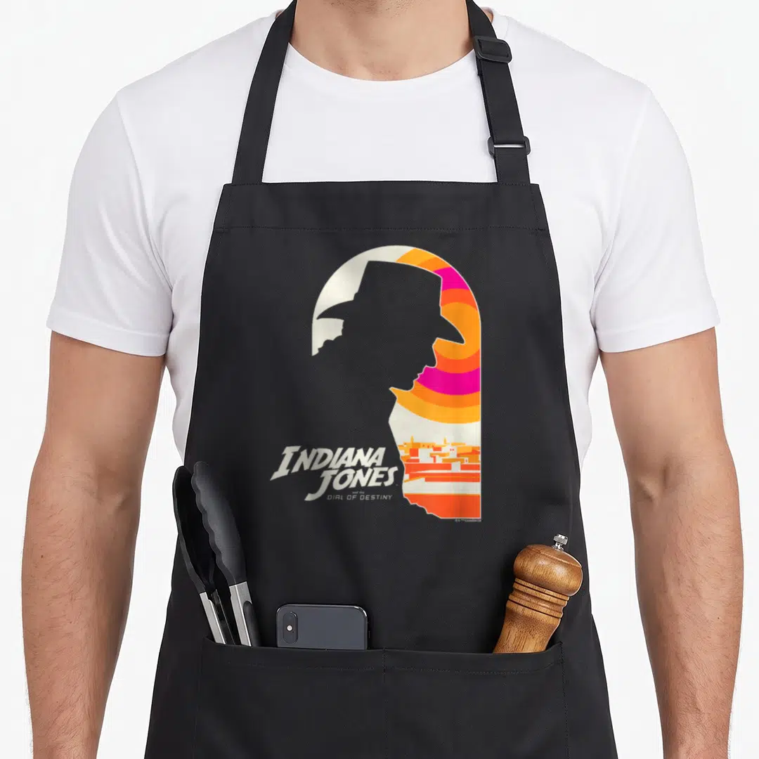 Dial indiana dunes apron - Grey silhouette of a man in a hat with striped background and Indiana Jones text — shown on a black cotton canvas apron against a white background