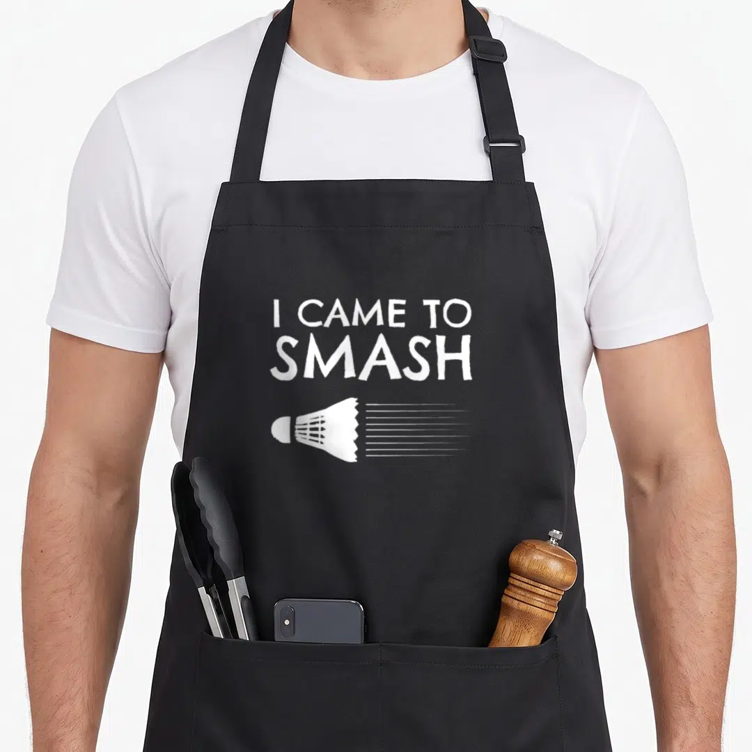 Smash badminton apron - White text I CAME TO SMASH above shuttlecock with motion lines — shown on a black cotton canvas apron against a white background