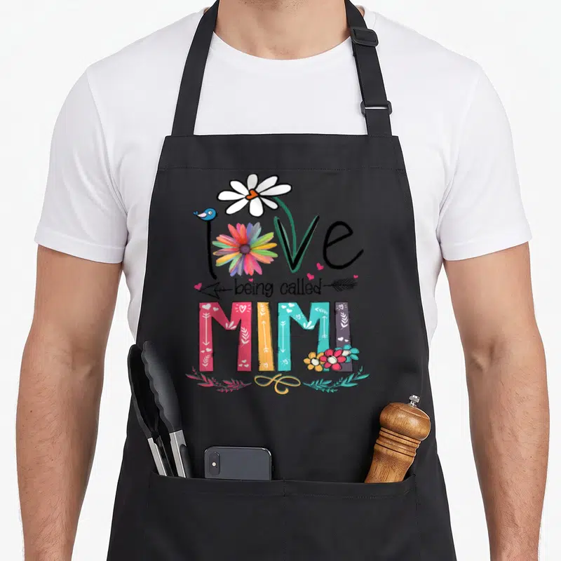 Called sunflower apron - Stacked text love being called MIMI with rainbow flower daisy bird arrow and decorative leaves — shown on a black cotton canvas apron against a white background
