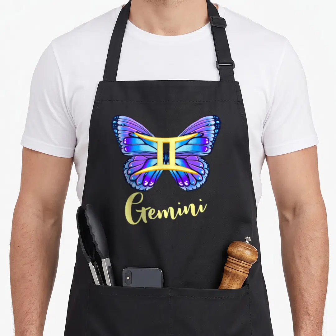 Gemini butterfly apron - Blue purple butterfly with golden zodiac symbol and yellow Gemini script — shown on a black cotton canvas apron against a white background