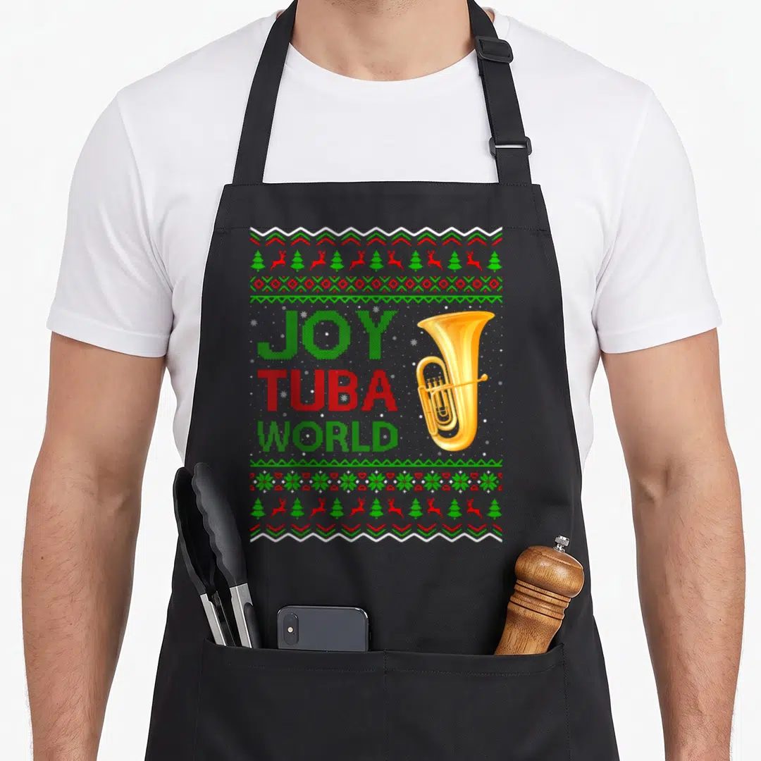 Joy ugly christmas apron - Pixel art tuba with JOY TUBA WORLD text and reindeer borders in red green and gold — shown on a black cotton canvas apron against a white background