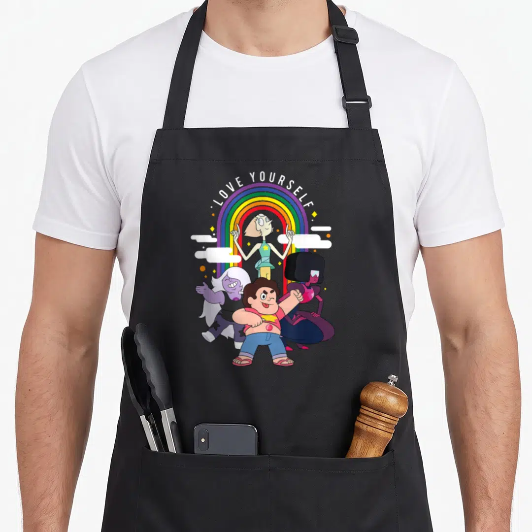 Steven pride apron - LOVE YOURSELF text over rainbow with four cartoon characters and white clouds — shown on a black cotton canvas apron against a white background