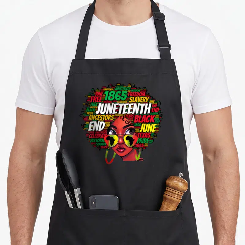 Juneteenth messy aprons - Woman with word-cloud hair saying Juneteenth 1865 freedom black pride wearing Africa map — shown on a black cotton canvas apron against a white background