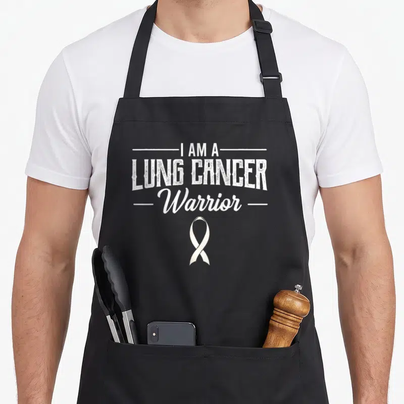 Warrior awareness ribbon apron - White I AM A LUNG CANCER Warrior text with ribbon symbol below — shown on a black cotton canvas apron against a white background