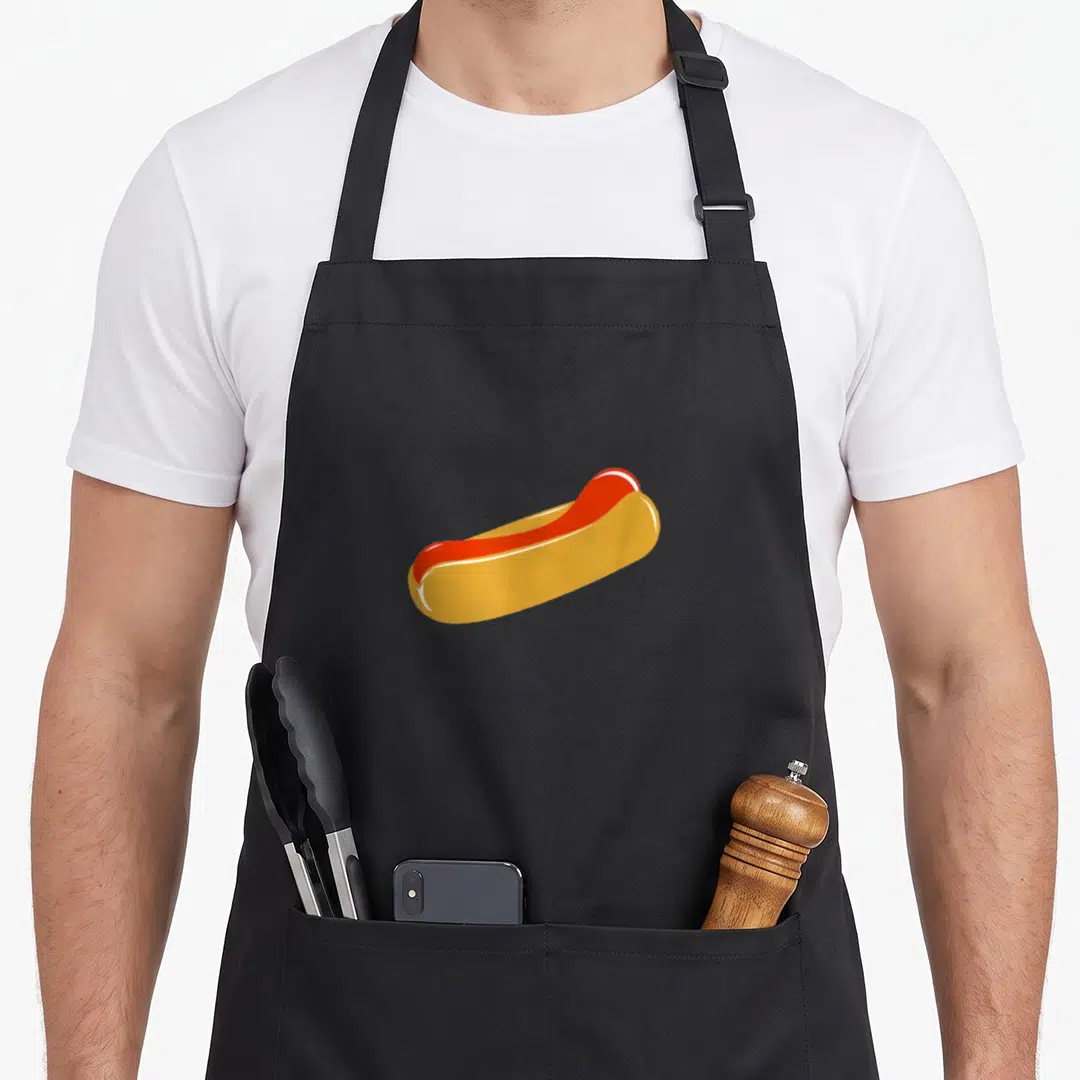 Wanted hot dog apron - Cartoon hot dog in bun with yellow bun and red sausage — shown on a black cotton canvas apron against a white background
