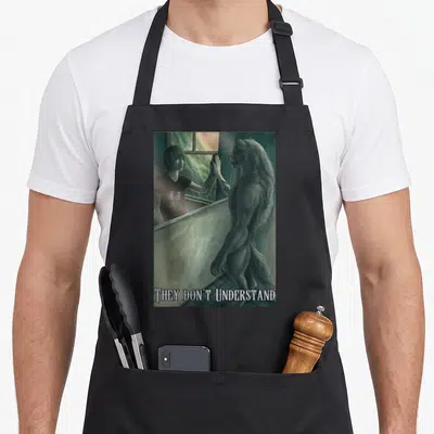 Werewolf meme apron - Werewolf looking into mirror reflecting a human man with text THEY DON'T UNDERSTAND below — shown on a black cotton canvas apron against a white background
