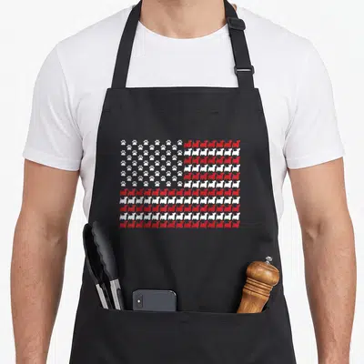 Scottie 4th of july apron - Red and white flag pattern made of rows of dog silhouettes and paw prints — shown on a black cotton canvas apron against a white background