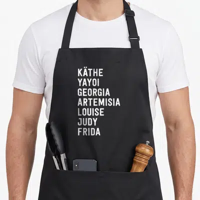 Artist famous aprons - Seven white artist names stacked vertically: Käthe Yayoi Georgia Artemisia Louise Judy Frida — shown on a black cotton canvas apron against a white background