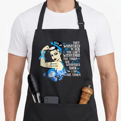 Month diabetes awareness apron - Cartoon woman flexing blue ribbon and storm quote text with blue roses — shown on a black cotton canvas apron against a white background