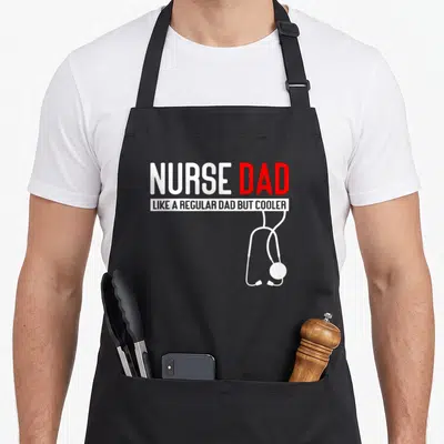 But nurses apron - NURSE DAD text with white stethoscope hanging below red and white lettering — shown on a black cotton canvas apron against a white background