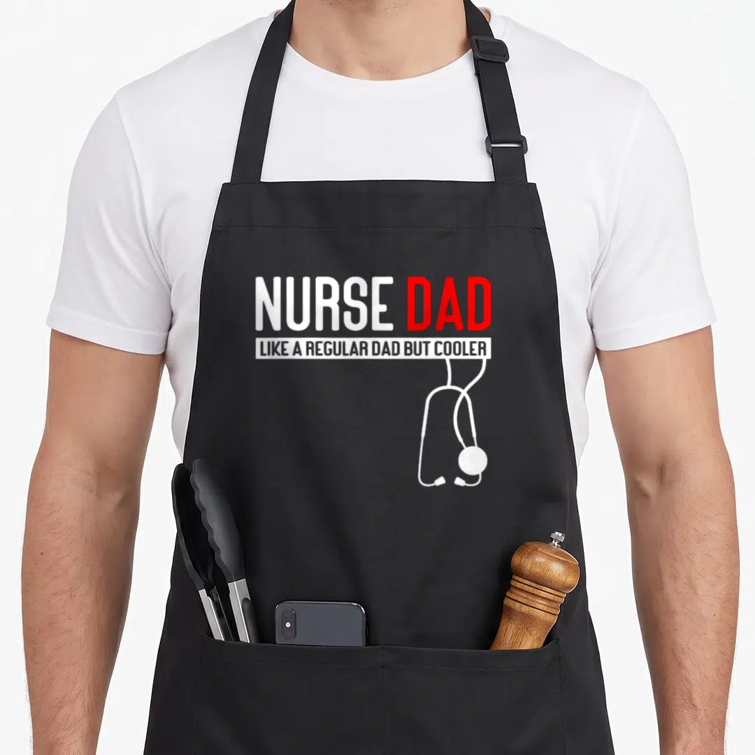 But nurses apron - NURSE DAD text with white stethoscope hanging below red and white lettering — shown on a black cotton canvas apron against a white background