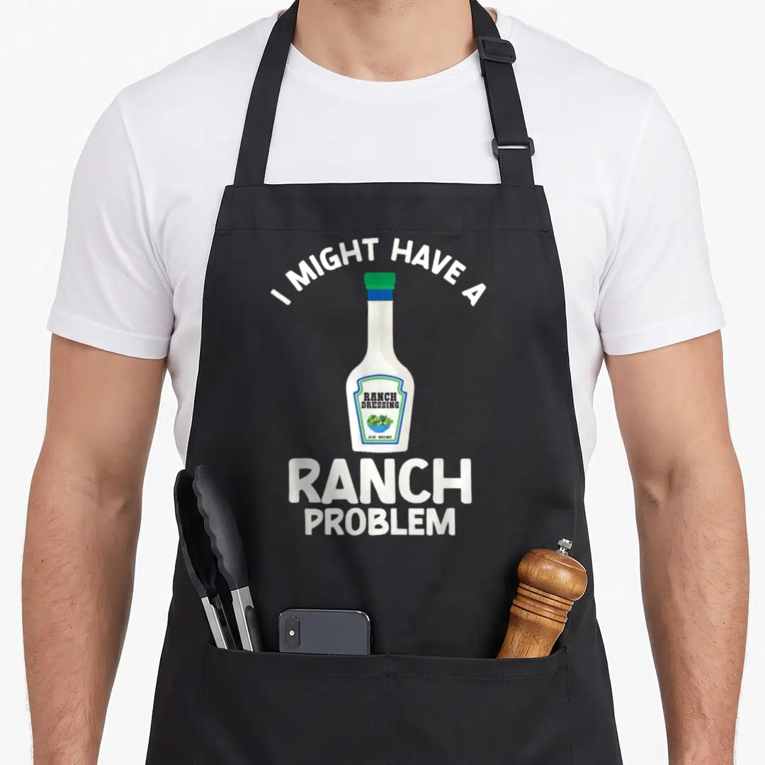 Ranch dressing halloween apron - Cartoon ranch dressing bottle with I Might Have A Ranch Problem text in white blue — shown on a black cotton canvas apron against a white background