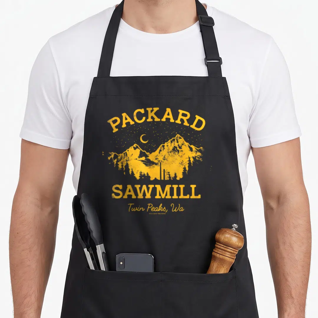 Packard twin peaks apron - Yellow distressed mountain graphic with arched PACKARD SAWMILL text and crescent moon — shown on a black cotton canvas apron against a white background