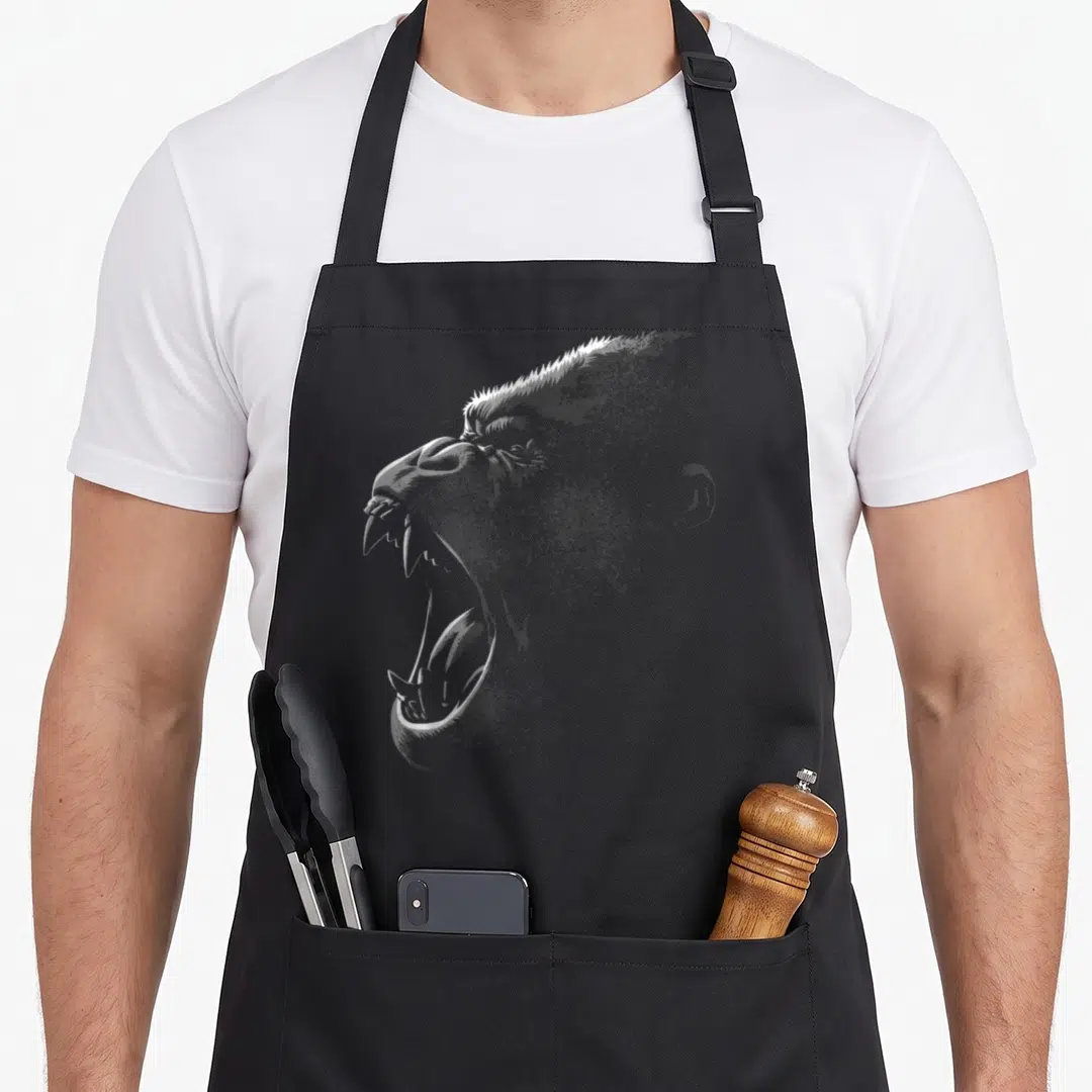 Leader gorilla apron - White line art of a roaring gorilla head facing left on black fabric — shown on a black cotton canvas apron against a white background