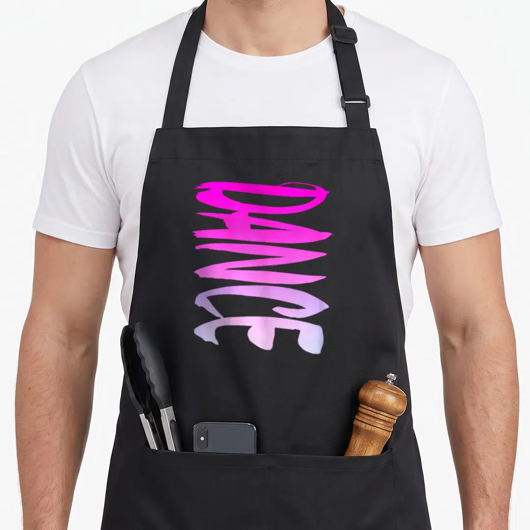 Dance colorful aprons - Vertical pink and purple brushstroke text reading Dance on a black background — shown on a black cotton canvas apron against a white background