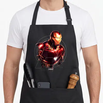Endgame general apron - Iron Man in red gold armor overlapping white Avengers logo and circle — shown on a black cotton canvas apron against a white background