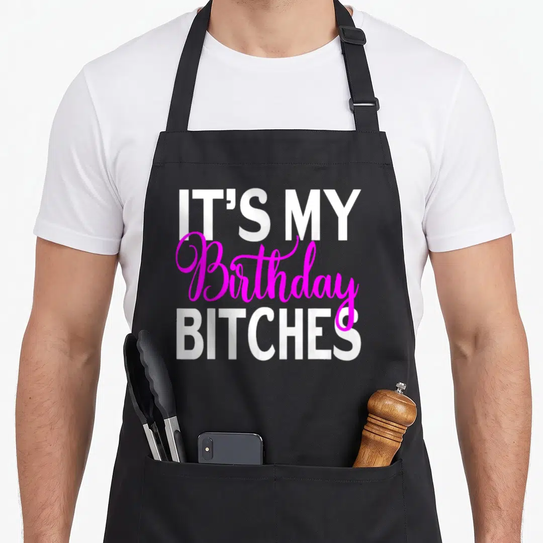 Cute occasion birthday apron - Stacked white and magenta text reading IT'S MY Birthday BITCHES — shown on a black cotton canvas apron against a white background