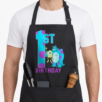 Mike birthday apron - Monsters Inc Mike Sulley 1ST BIRTHDAY cyan purple blue green cartoon — shown on a black cotton canvas apron against a white background