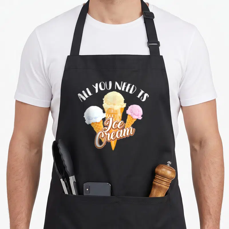 Dessert ice cream apron - Three ice cream cones in white yellow blue pink and orange under arched text — shown on a black cotton canvas apron against a white background