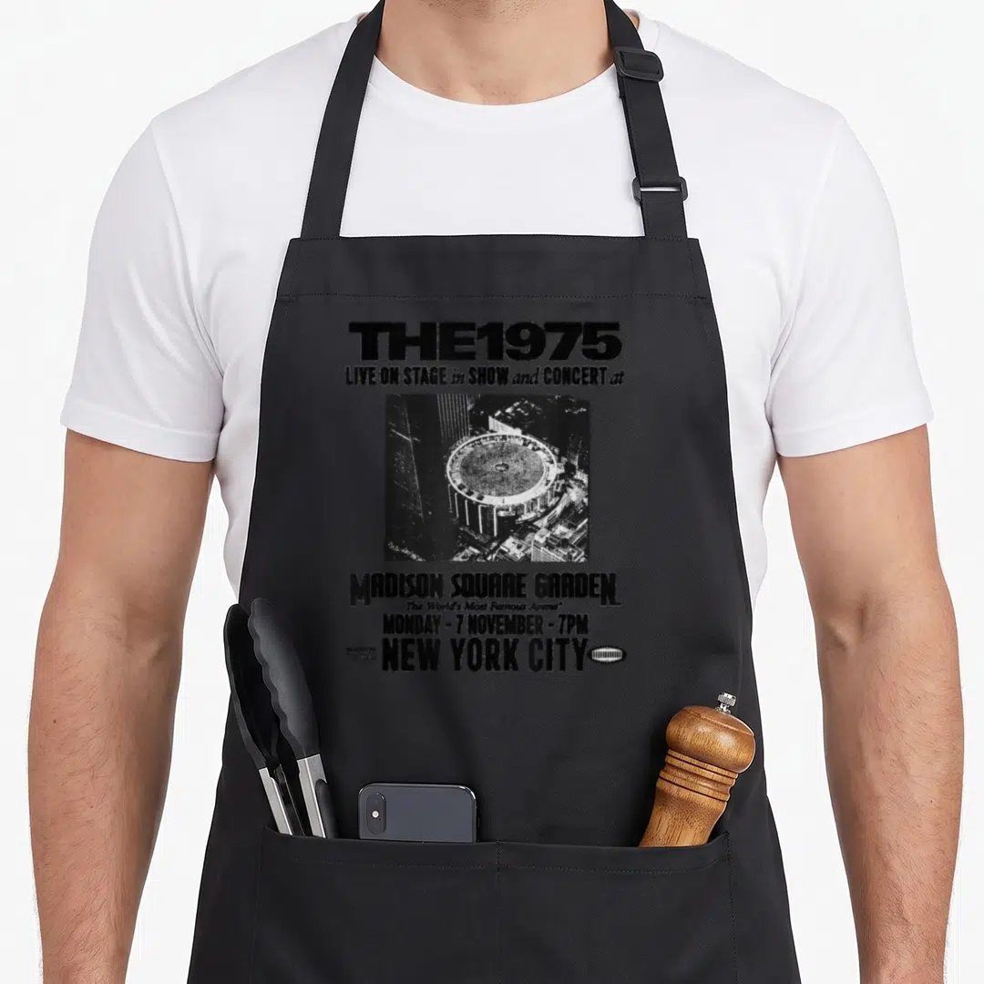 Live stage apron - Distressed black and white MSG concert poster text with aerial arena photo — shown on a black cotton canvas apron against a white background