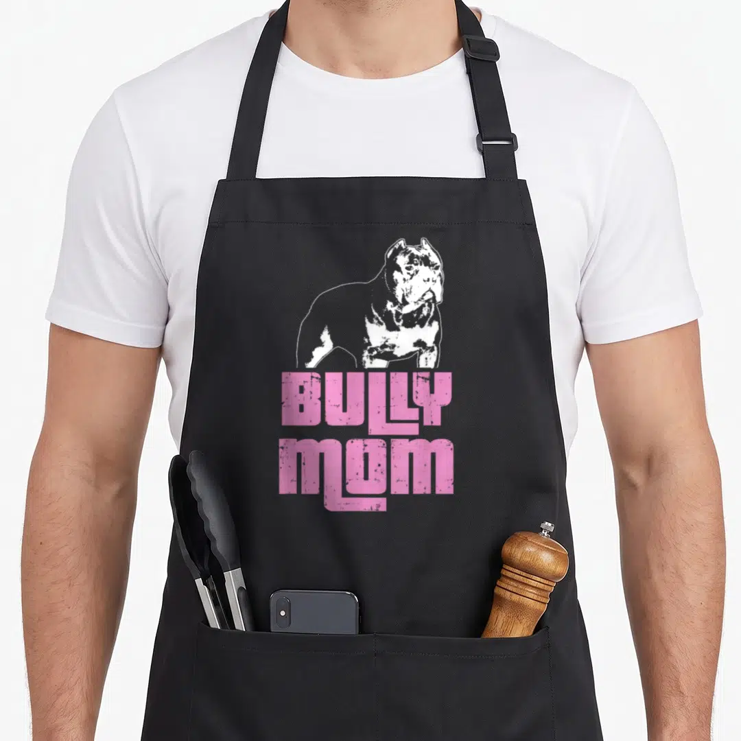 Bully custom dog apron - White dog silhouette above pink distressed BULLY MOM text on black background — shown on a black cotton canvas apron against a white background
