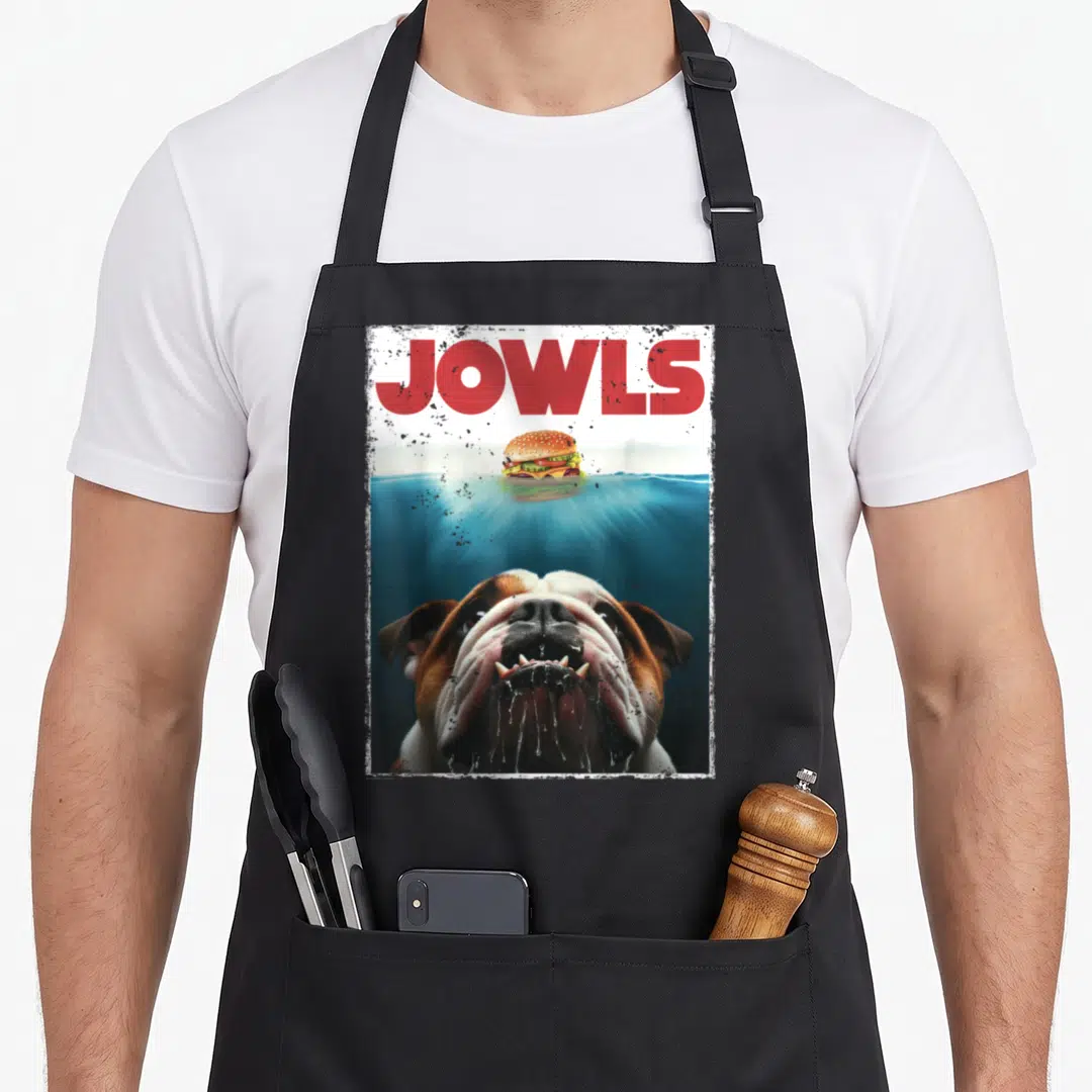 Bulldog english aprons - JOWLS text above bulldog diving underwater for a burger with distressed border — shown on a black cotton canvas apron against a white background