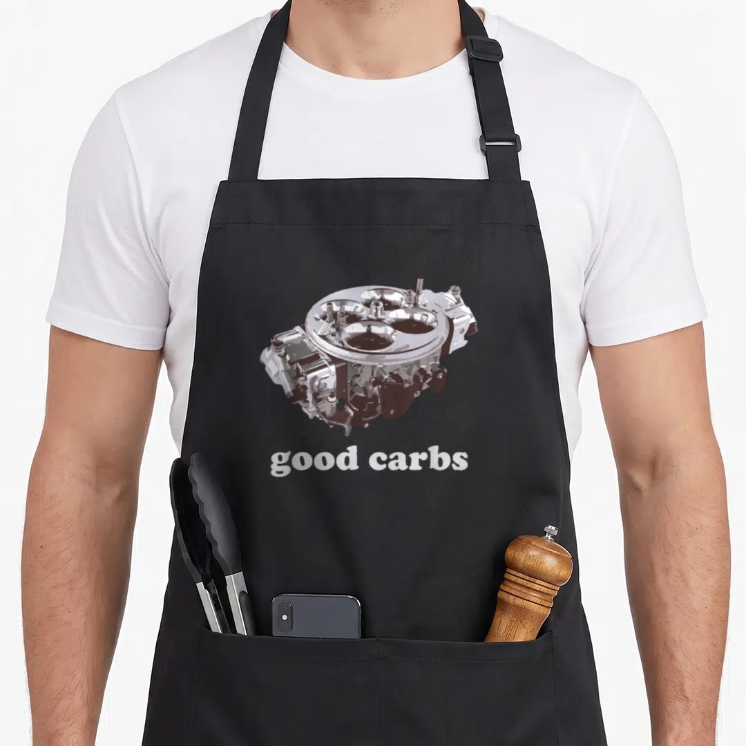 Carb car apron - Realistic silver 4-barrel carburetor illustration above white good carbs text on grey background — shown on a black cotton canvas apron against a white background
