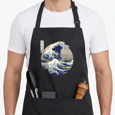 Kanagawa japanese wave apron - Circular print of crashing wave with boats and kanji text box — shown on a black cotton canvas apron against a white background