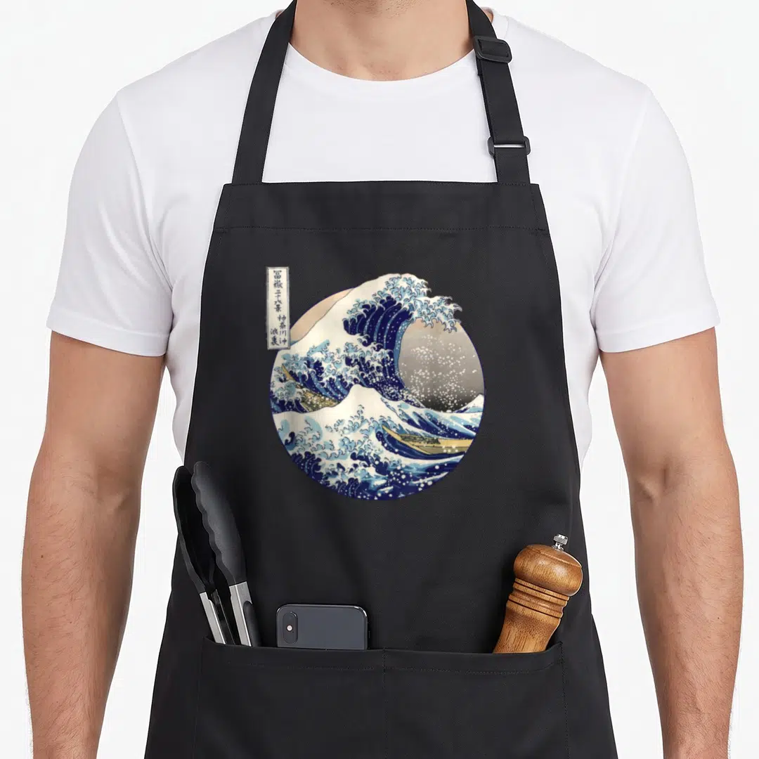 Kanagawa japanese wave apron - Circular print of crashing wave with boats and kanji text box — shown on a black cotton canvas apron against a white background
