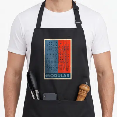 Synthesizer nerd apron - Retro modular synthesizer panel with red and blue halves and the word MODULAR at the bottom — shown on a black cotton canvas apron against a white background