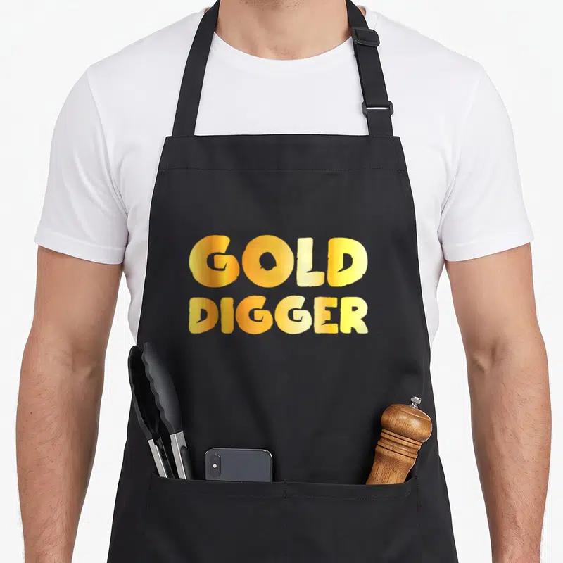 Digger geek apron - Stacked gold and yellow text reading GOLD DIGGER — shown on a black cotton canvas apron against a white background