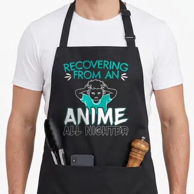 Nighter anime apron - Teal and white text Recovering From An Anime All Nighter around a tired cartoon person — shown on a black cotton canvas apron against a white background